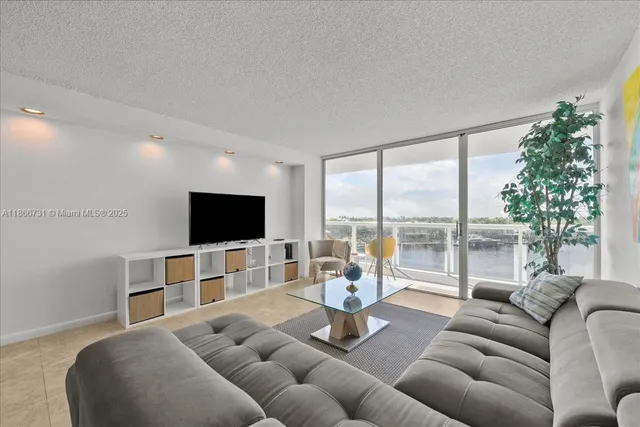 a living room with furniture a flat screen tv and a large window
