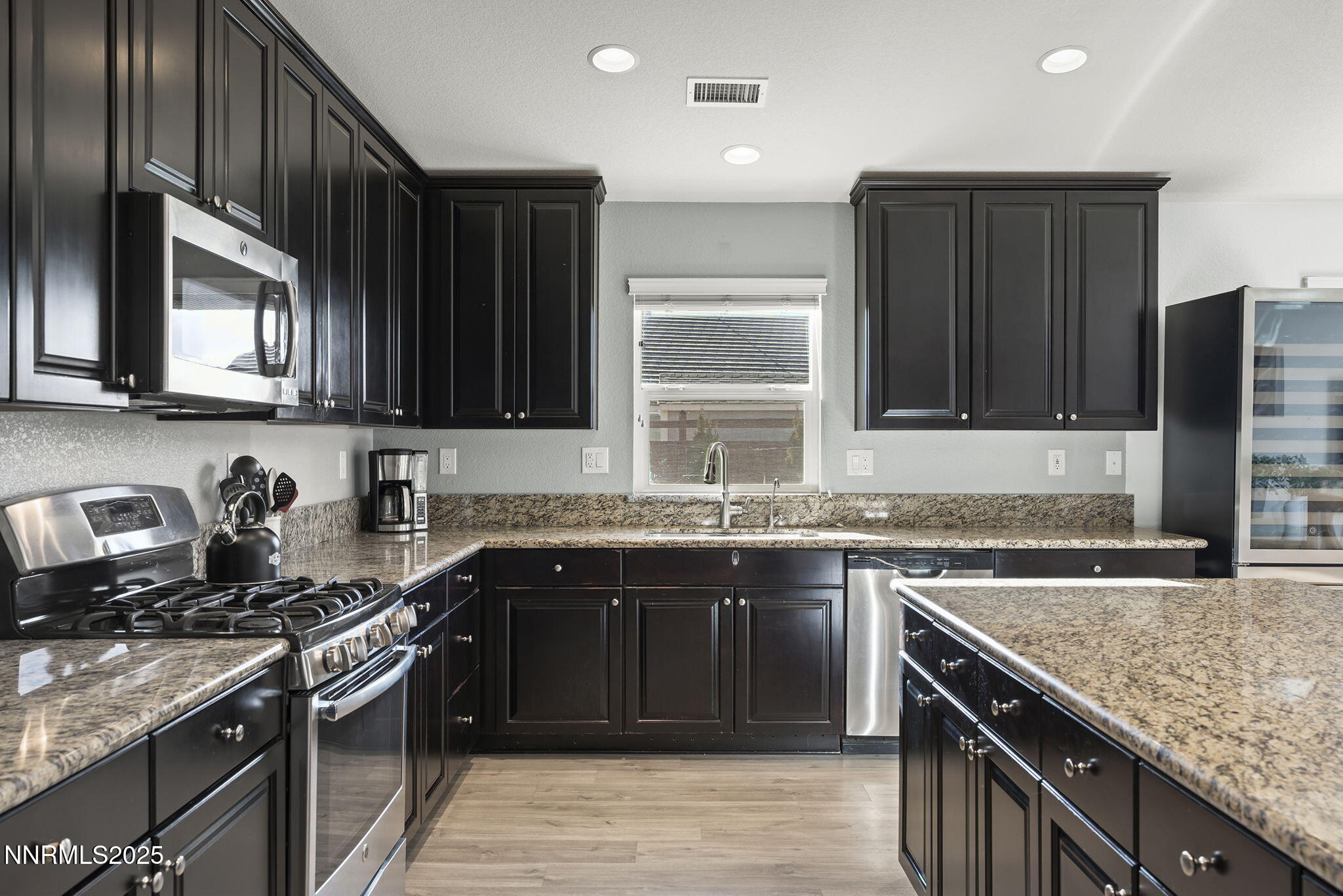 7707 Rhythm Circle Sparks, NV 89436 - Photo 9 of 30 a kitchen with stainless steel appliances granite countertop a stove sink microwave and cabinets