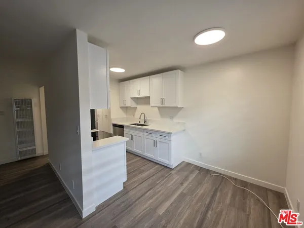 a kitchen with a refrigerator and white cabinets