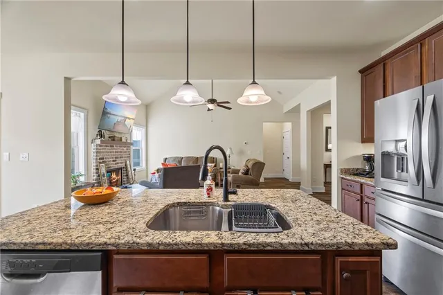 a kitchen with kitchen island granite countertop a sink stainless steel appliances and a chandelier