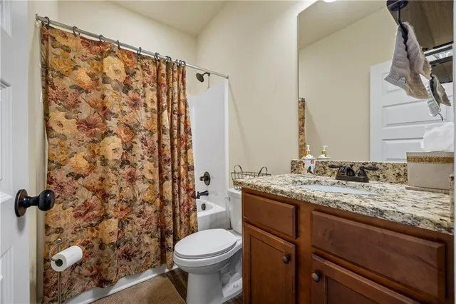 a bathroom with a granite countertop sink toilet and shower