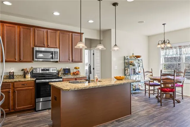 a kitchen with stainless steel appliances granite countertop a stove refrigerator a dining table and chairs with wooden floor