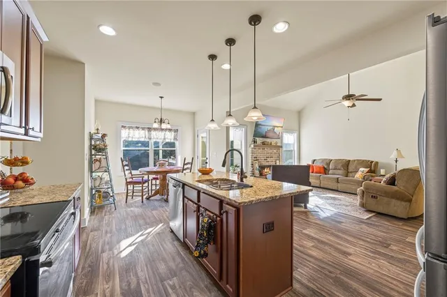 a open kitchen with stainless steel appliances granite countertop a stove oven and a dining table with wooden floor