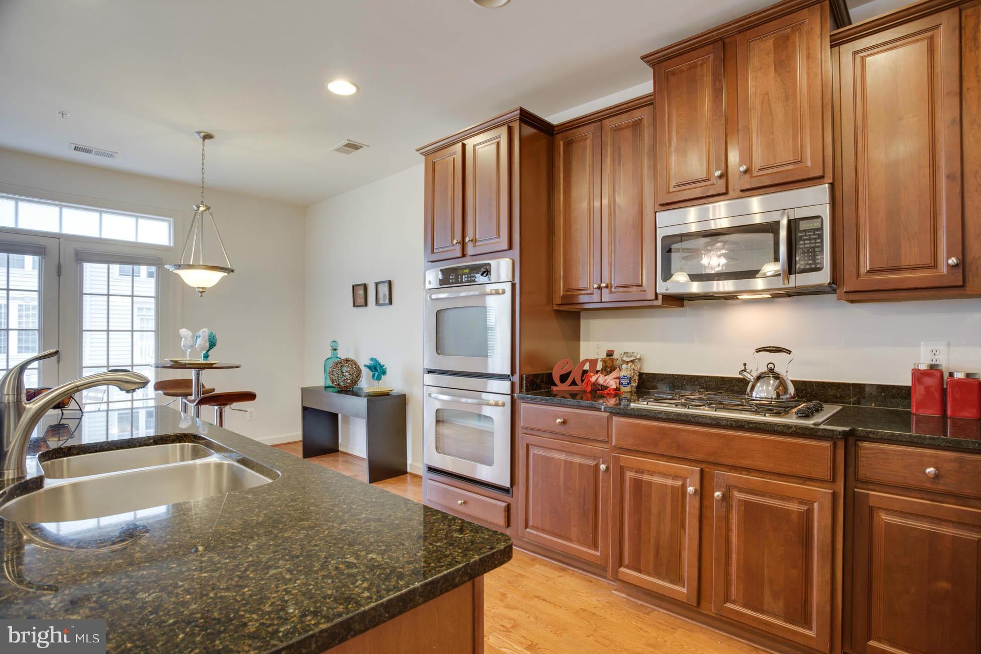 5723 Callcott Way, Unit M Alexandria, VA 22312 - Photo 12 of 28 a kitchen with kitchen island granite countertop a sink stove and cabinets
