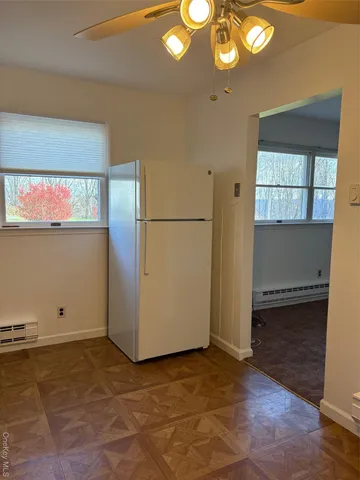 a view of a refrigerator in kitchen and an empty room