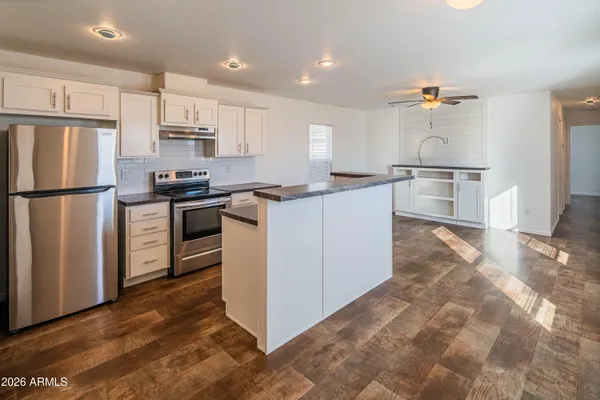 a kitchen with granite countertop a refrigerator stove top oven and sink