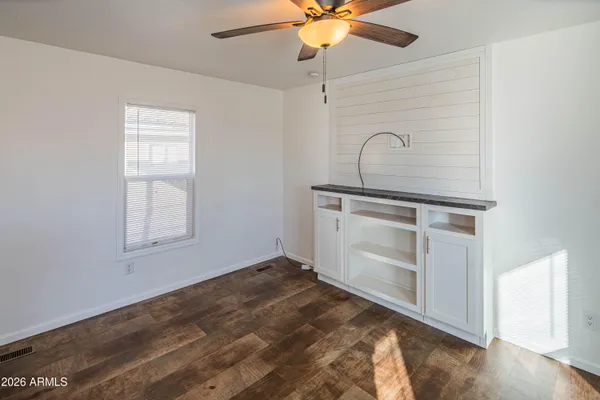 a view of an empty room with window and chandelier fan
