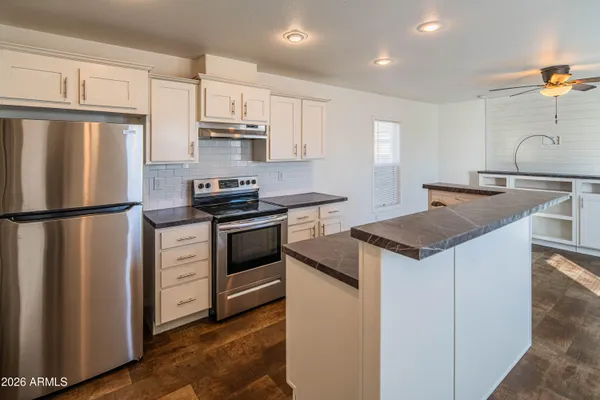 a kitchen with granite countertop a sink stove and refrigerator