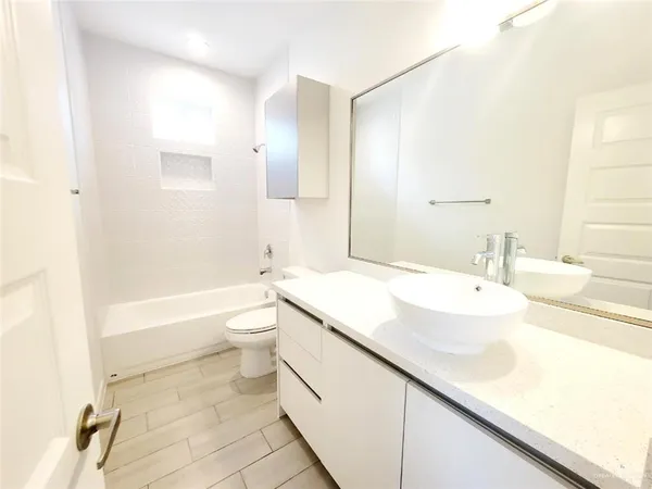 a bathroom with a granite countertop sink a toilet and bathtub