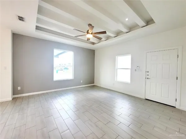 an empty room with wooden floor chandelier fan and windows