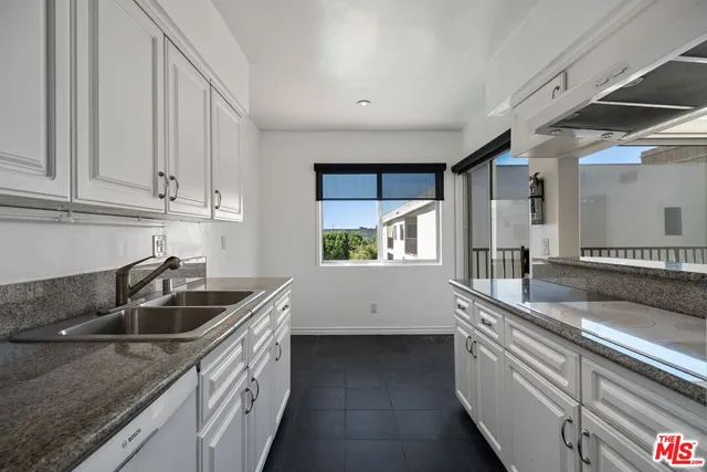 a kitchen with granite countertop a sink and cabinets