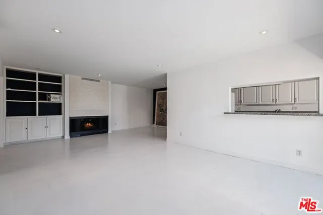 an empty room with a fireplace and cabinets