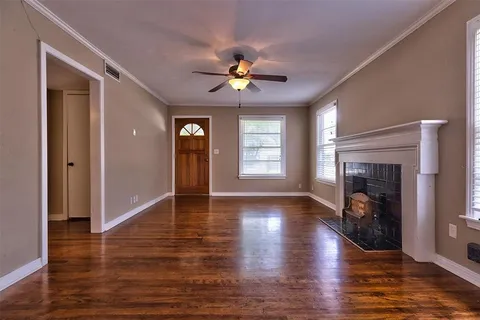 an empty room with wooden floor fireplace and windows