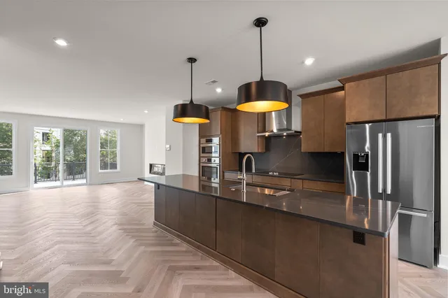 a kitchen with stainless steel appliances granite countertop a sink a stove and a refrigerator