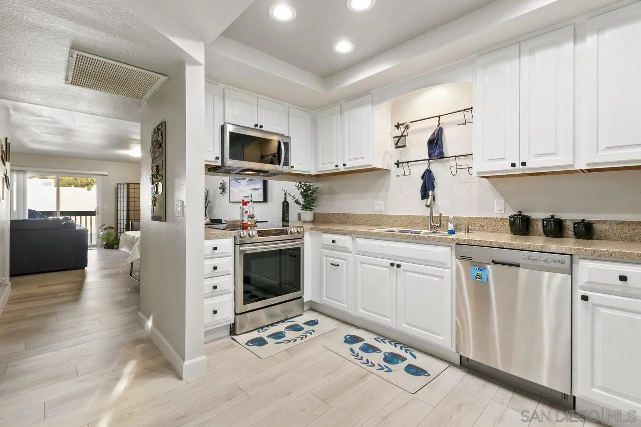 6381 Rancho Mission Road, Unit 6 San Diego, CA 92108 - Photo 12 of 30 a kitchen with granite countertop white cabinets and white appliances