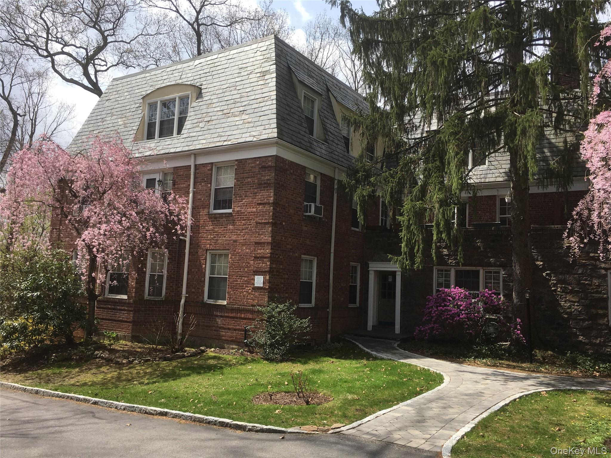 a view of a brick house with many windows and a yard