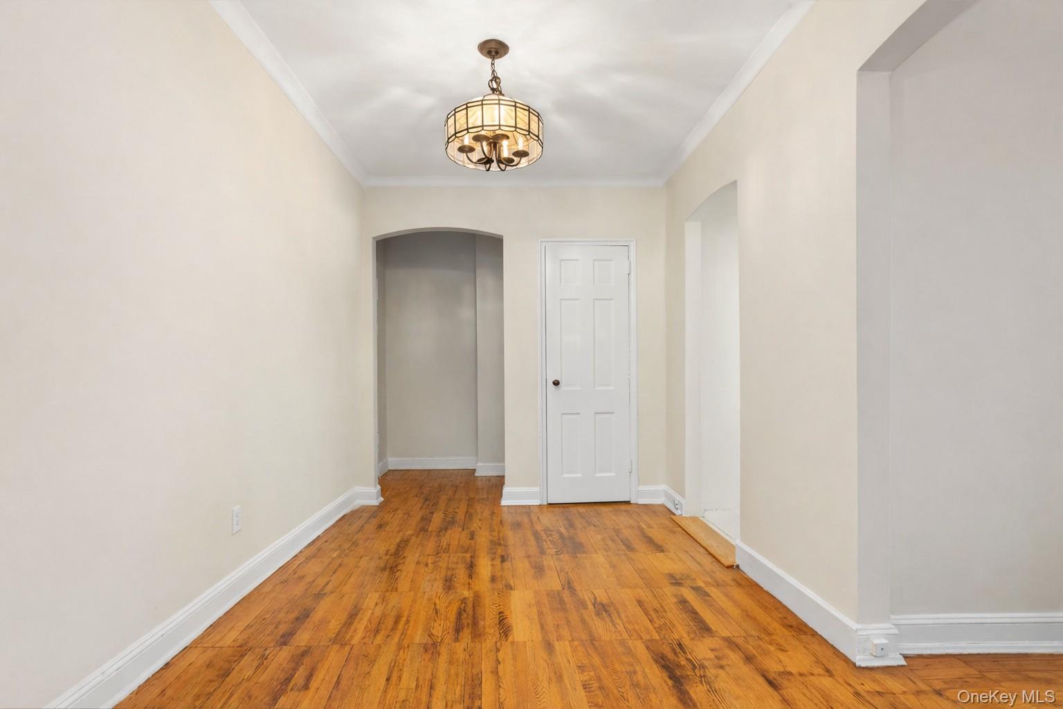 60 Pinewood Road, Unit 1B Hartsdale, NY 10530 - Photo 8 of 27 Dining area featuring arched walkways, hardwood floors, a chandelier, and crown molding.