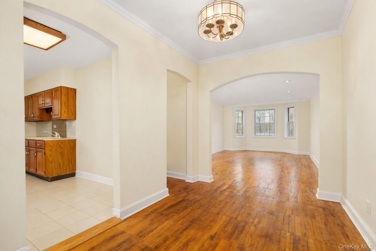 60 Pinewood Road, Unit 1B Hartsdale, NY 10530 - Photo 9 of 27 Dining area with arched walkways, hardwood floors, a chandelier and crown molding.