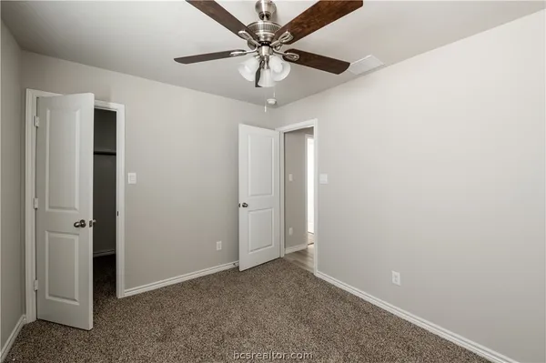 an empty room with a chandelier fan and windows