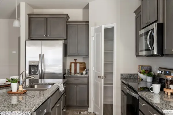 a kitchen with granite countertop a sink stove and refrigerator