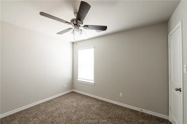 an empty room with a window and a fan