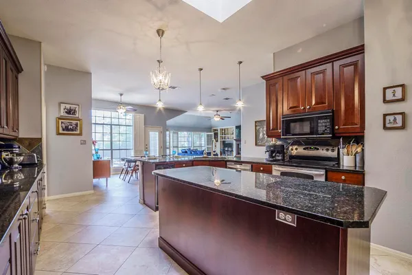 a large kitchen with granite countertop a large counter top space appliances and cabinets