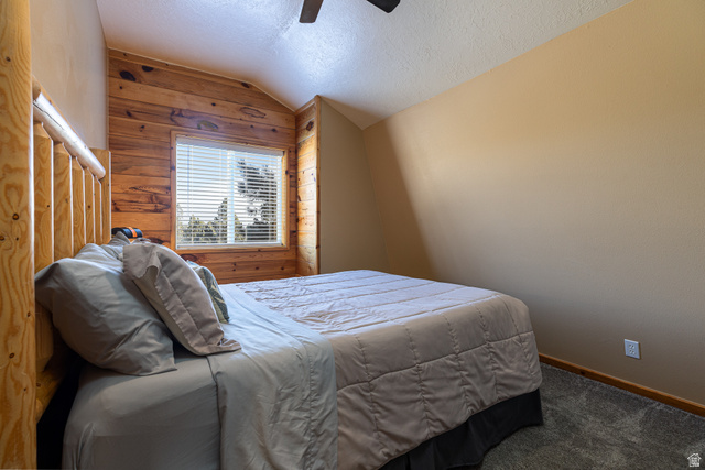 1505 West Elk Ridge Drive Alton, UT 84710 - Photo 24 of 53 Carpeted bedroom with a textured ceiling, lofted ceiling, wooden walls, and ceiling fan