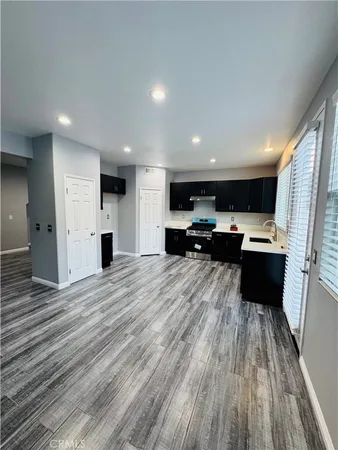 a view of kitchen with stainless steel appliances kitchen island refrigerator stove and wooden floor