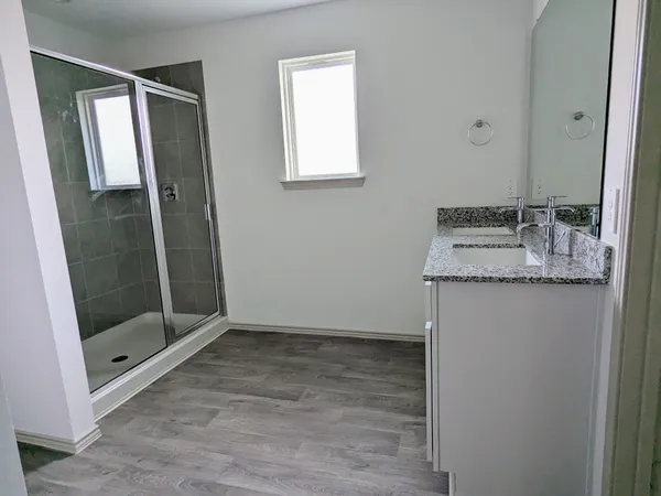 a bathroom with a granite countertop sink a mirror and shower
