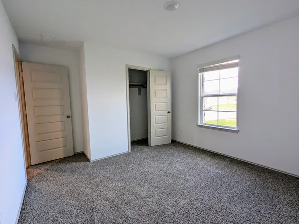 an empty room with closet and windows