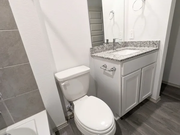 a bathroom with a granite countertop toilet sink and mirror