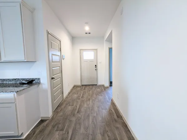 a view of a kitchen with wooden floor electronic appliances and cabinets