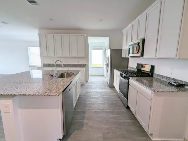 a kitchen with granite countertop a sink and white cabinets