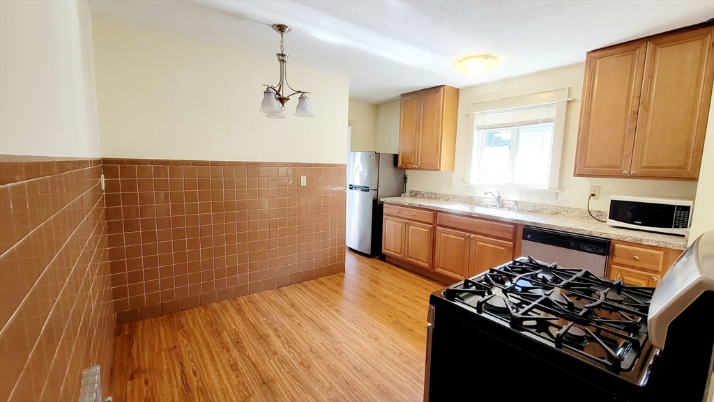 149 Powder House Boulevard, Unit 149 Somerville, MA 02144 - Photo 2 of 11 a kitchen with a sink stove and cabinets
