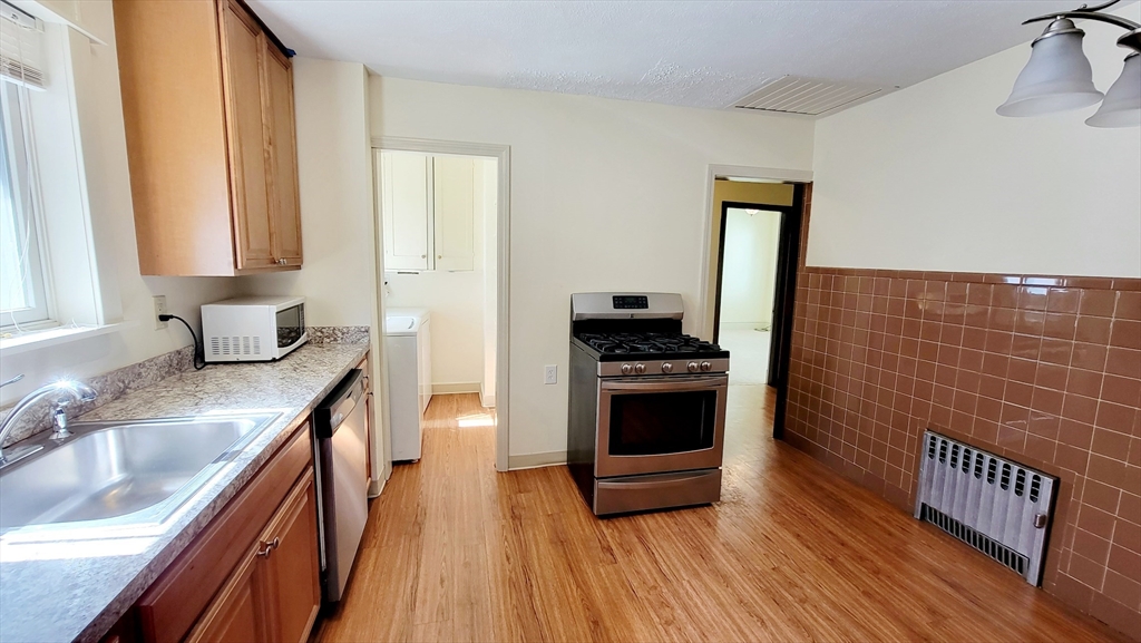 149 Powder House Boulevard, Unit 149 Somerville, MA 02144 - Photo 3 of 11 a kitchen with granite countertop a stove and a sink