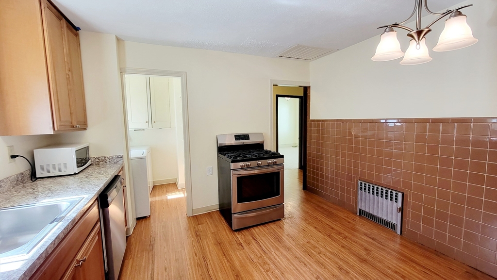149 Powder House Boulevard, Unit 149 Somerville, MA 02144 - Photo 4 of 11 a kitchen with granite countertop a stove and a sink