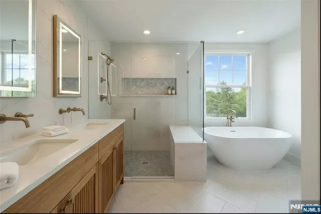 a bathroom with a double vanity sink mirror and bathtub