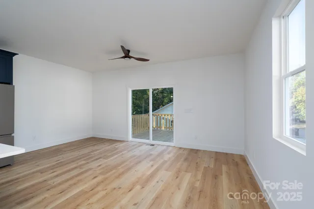 a view of an empty room with wooden floor and a window