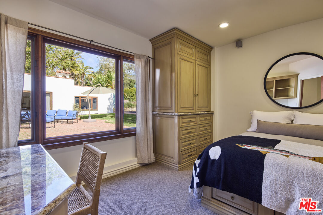 6138 Ramirez Canyon Road Malibu, CA 90265 - Photo 18 of 31 a bedroom with a bed lamp and a large window