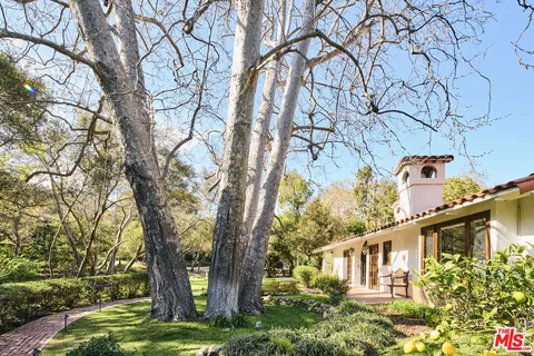 a front view of a house with lots of flowers and trees