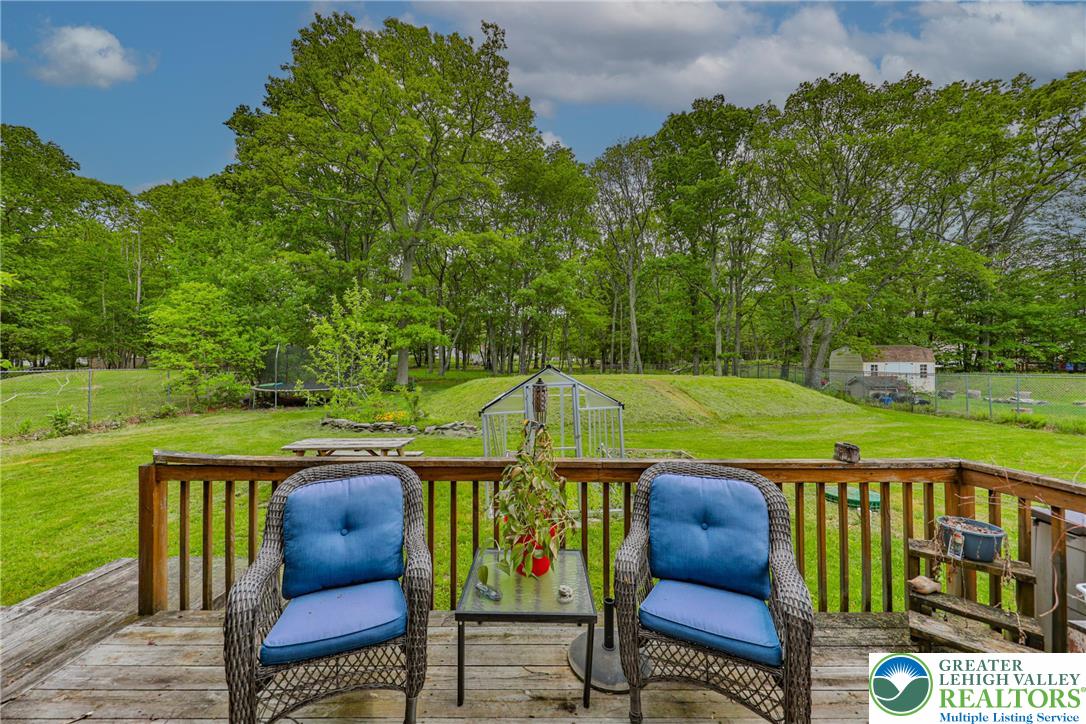 4608 Pine Ridge Drive West Bushkill, PA 18324 - Photo 54 of 62 A spacious backyard vista, framed by a wooden deck, features verdant trees and a charming greenhouse.