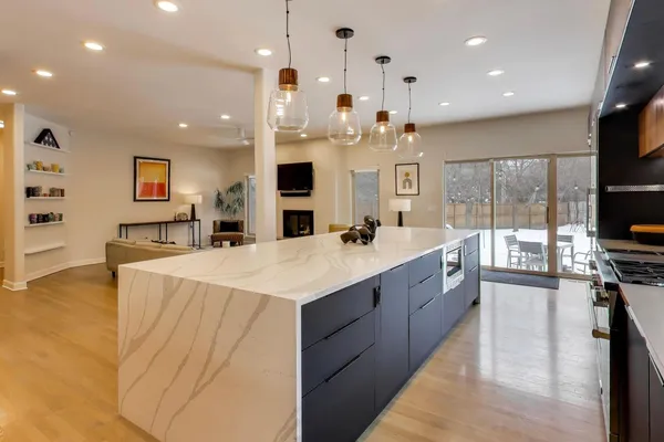 a large white kitchen with a large counter top stainless steel appliances and a chandelier