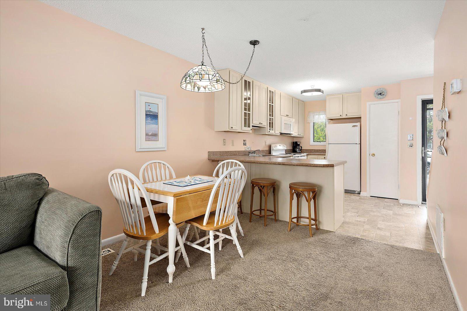 614 Osprey Road, Unit D Ocean City, MD 21842 - Photo 12 of 60 a view of a dining room with furniture and a chandelier