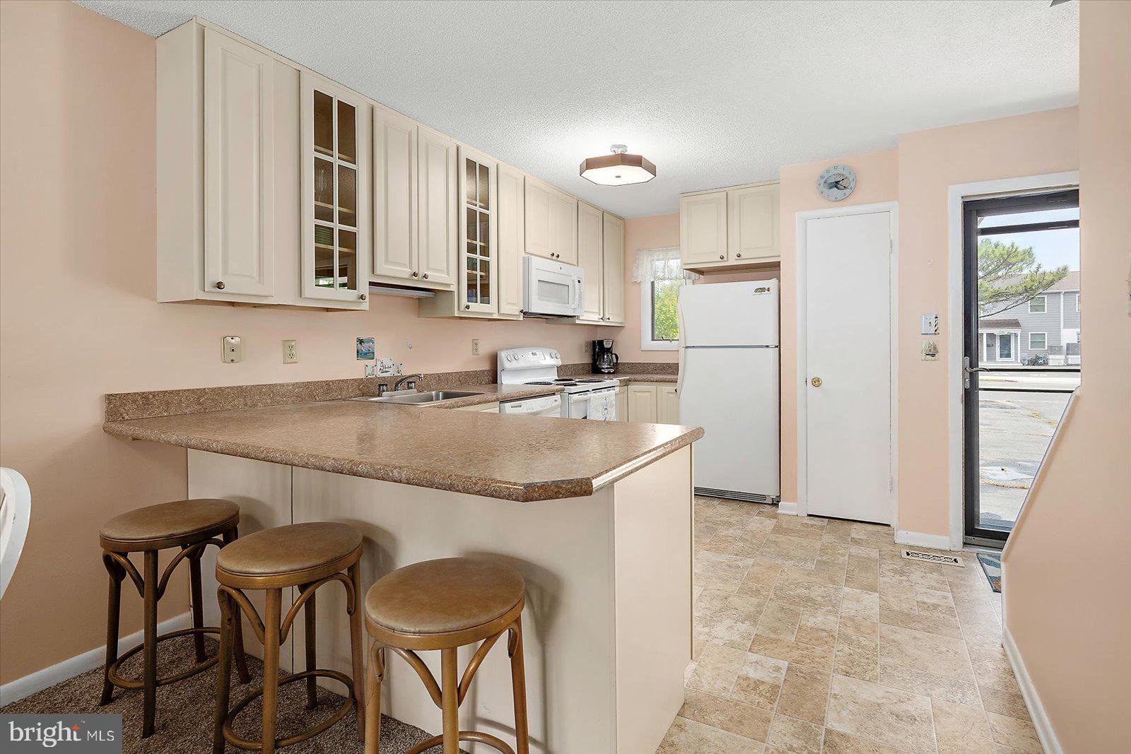614 Osprey Road, Unit D Ocean City, MD 21842 - Photo 13 of 60 a kitchen with stainless steel appliances granite countertop a table chairs sink refrigerator and cabinets