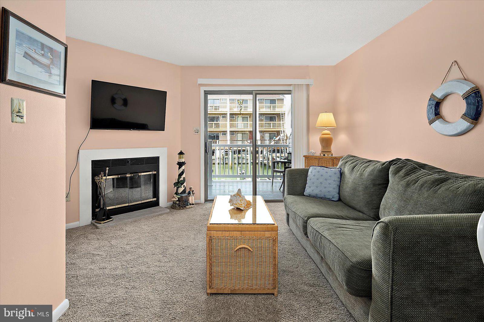 614 Osprey Road, Unit D Ocean City, MD 21842 - Photo 7 of 60 a living room with furniture a fireplace and a flat screen tv