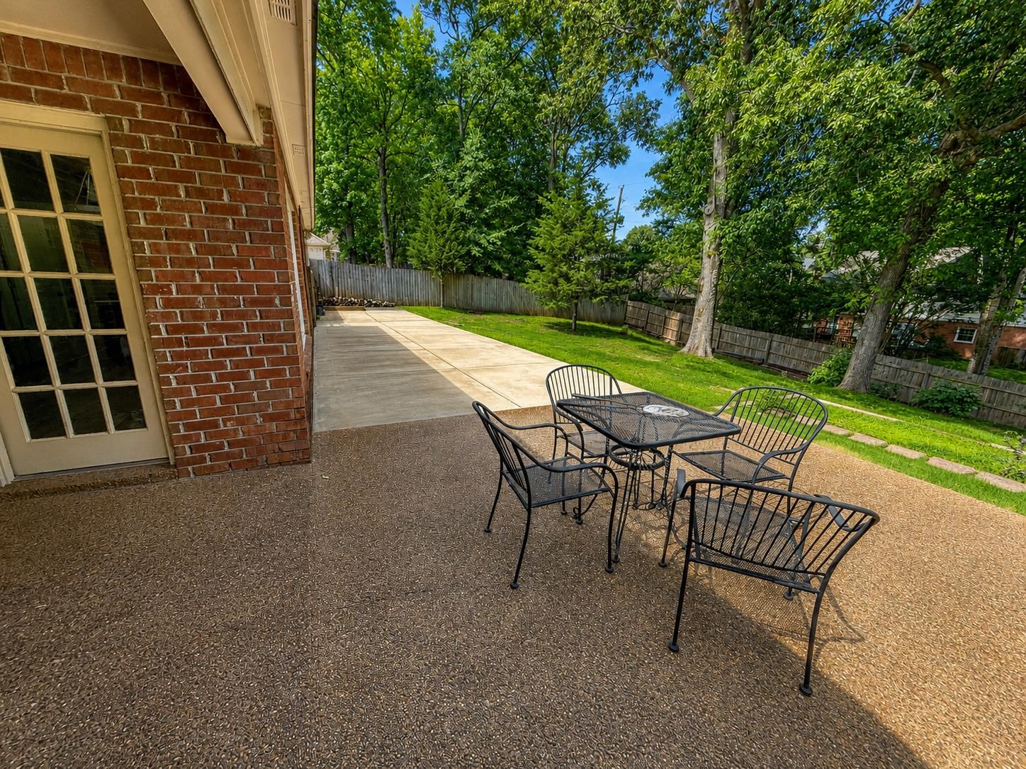 326 South Sanga Road Cordova, TN 38018 - Photo 29 of 32 Expansive aggregate patio with an adjacent concrete pathway, framed by a brick exterior and a privacy fence