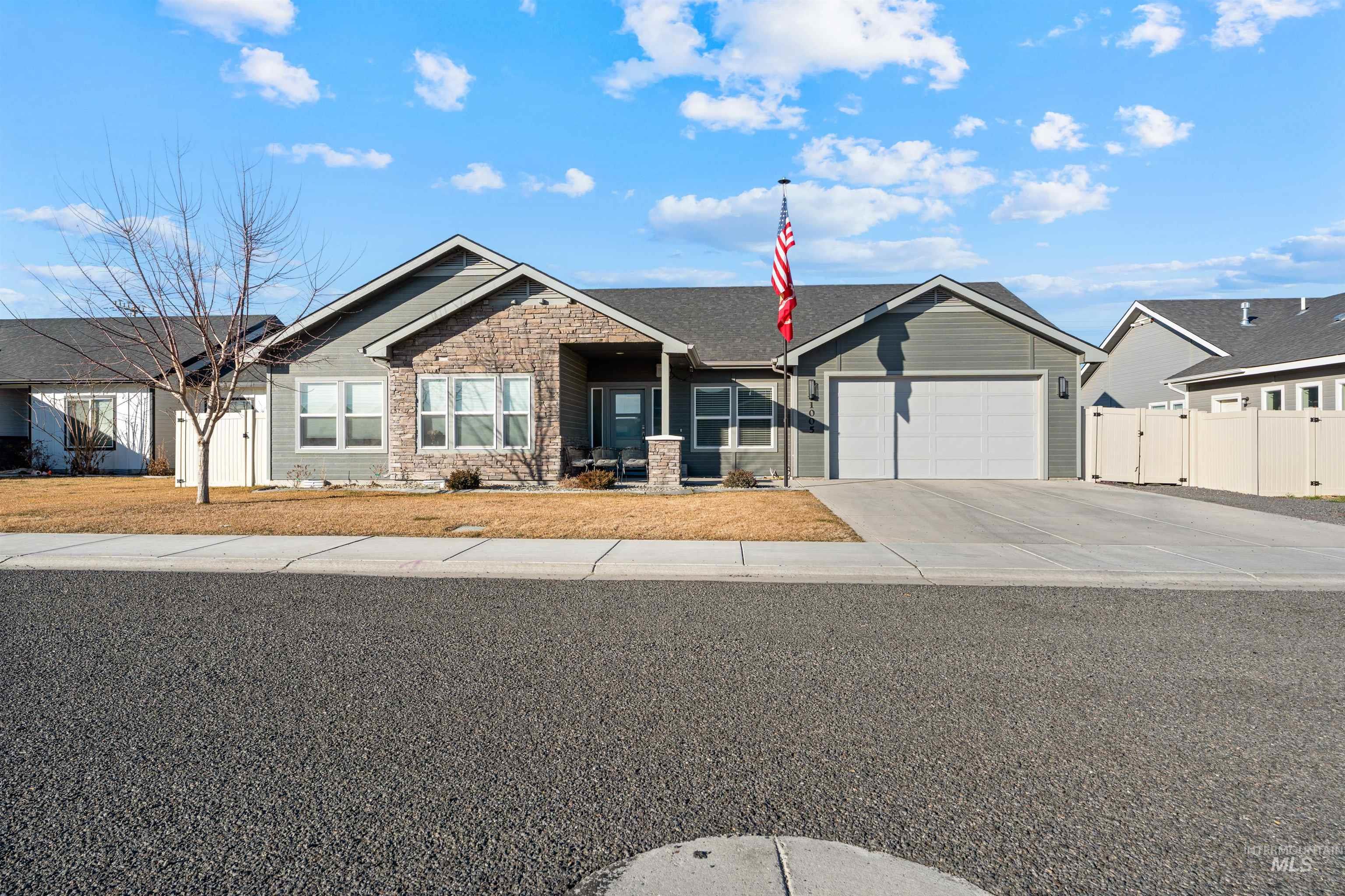 Ranch-style house featuring stone siding, concrete driveway, an attached garage, and a gate
