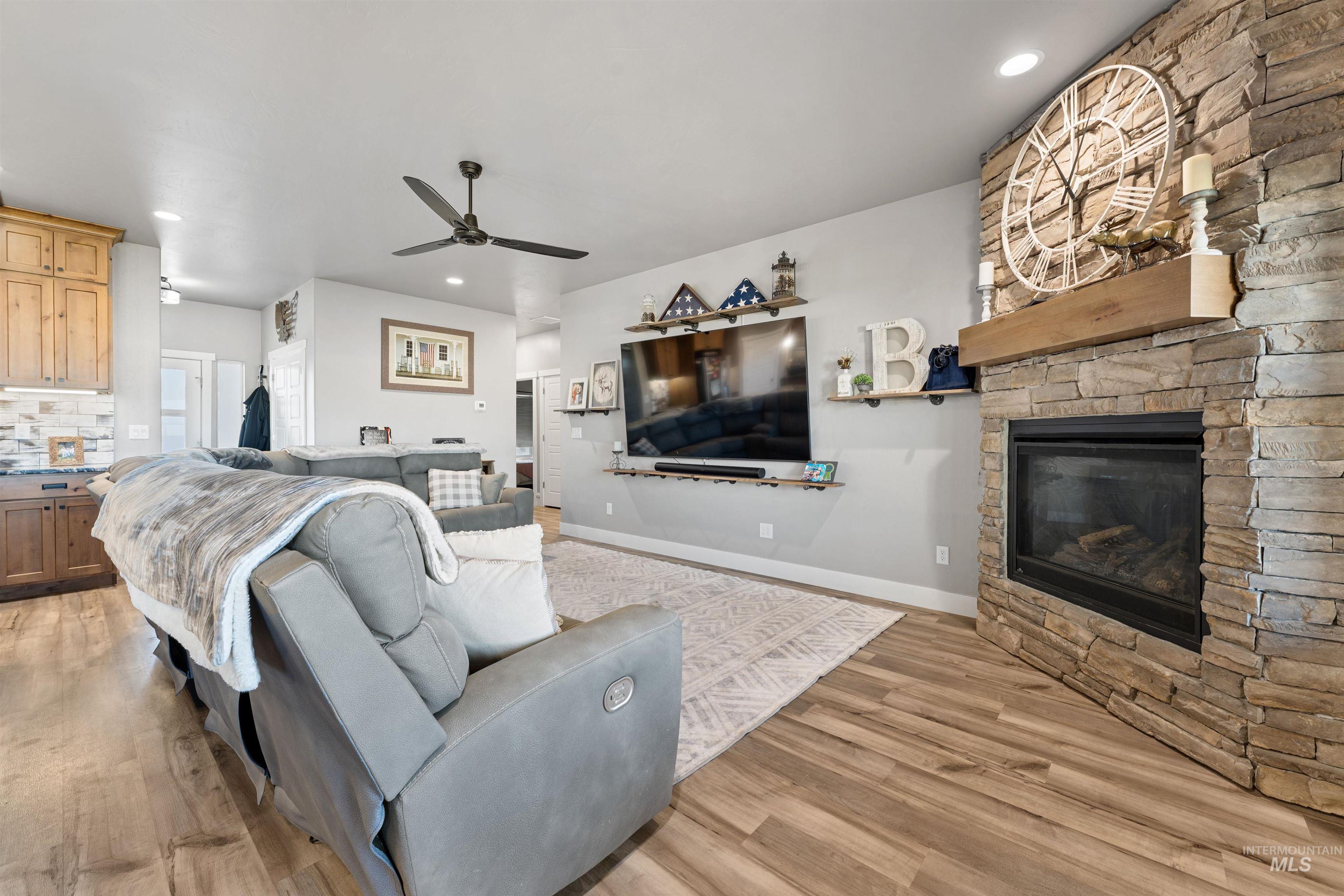 1005 Kenbrook Loop Twin Falls, ID 83301 - Photo 6 of 47 Living room featuring a stone fireplace, light wood-type flooring, a ceiling fan, and recessed lighting