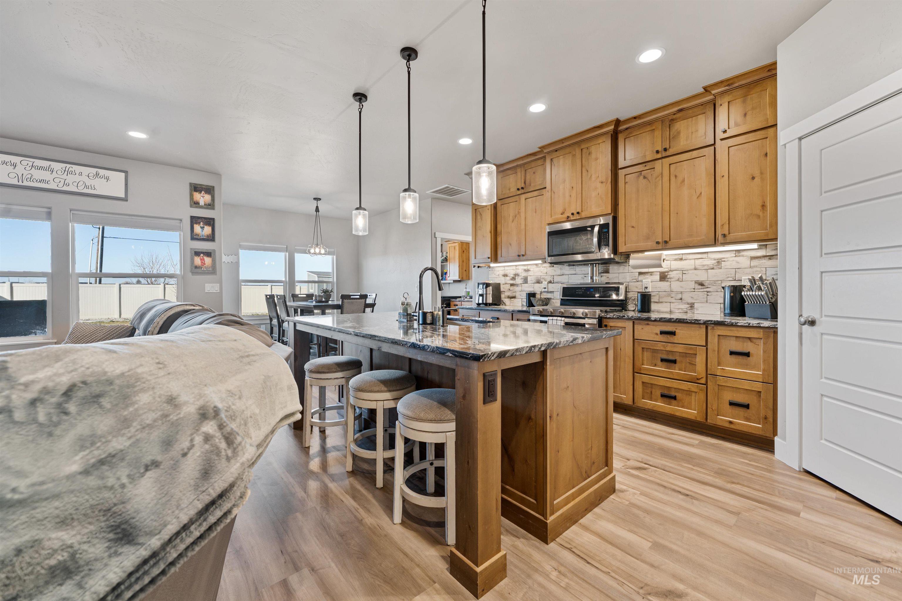 1005 Kenbrook Loop Twin Falls, ID 83301 - Photo 47 of 47 Kitchen with a breakfast bar, dark stone counters, open floor plan, a center island with sink, and light wood-style flooring