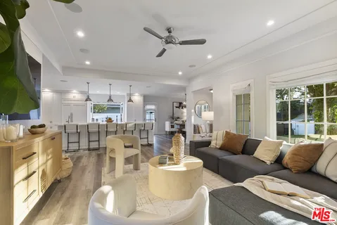 a room with stainless steel appliances kitchen island granite countertop a table chairs and a wooden floor